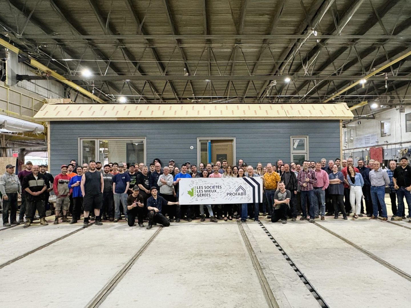 Ensemble de travailleur d'usine de PROFAB qui tient une affiche des sociétés les mieux gérées.